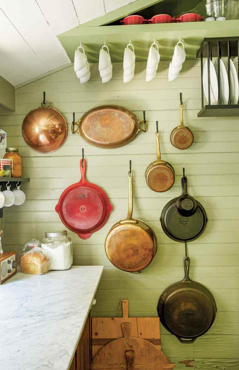 NO CABINETS. NO PROBLEM. Wall-hung cookware, coffee cup hooks, and an ingenious plate rack make alternative storage solutions seem like a design plus rather than a necessary evil.