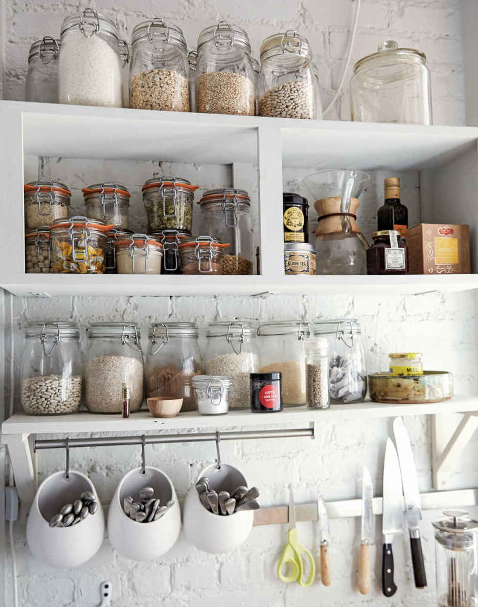 A PLACE FOR EVERYTHING. IKEA shelving and simple, open boxes mounted on the walls provide all the storage this kitchen needs at a minimal expense. Hanging cubbies for flatware eliminate the need for a drawer.
