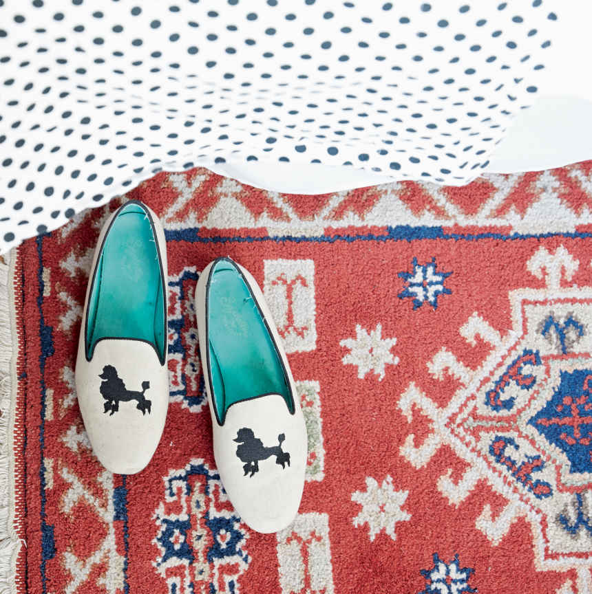 SOFT FOOTING. The attention to color and detail in this starter rental is amazing. Here, one of two small Persian rugs pops against the dotted sheets and emerald-soled slippers.