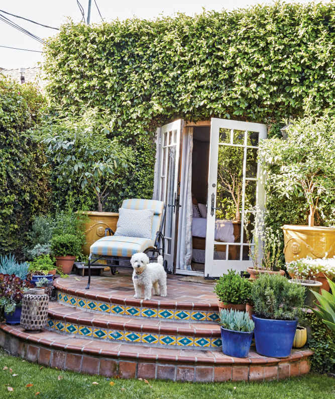 SUN PATIO. The owners opened up an exterior wall to connect the bedroom to their yard, adding elegant French doors and steps that are now home to dozens of potted plants.