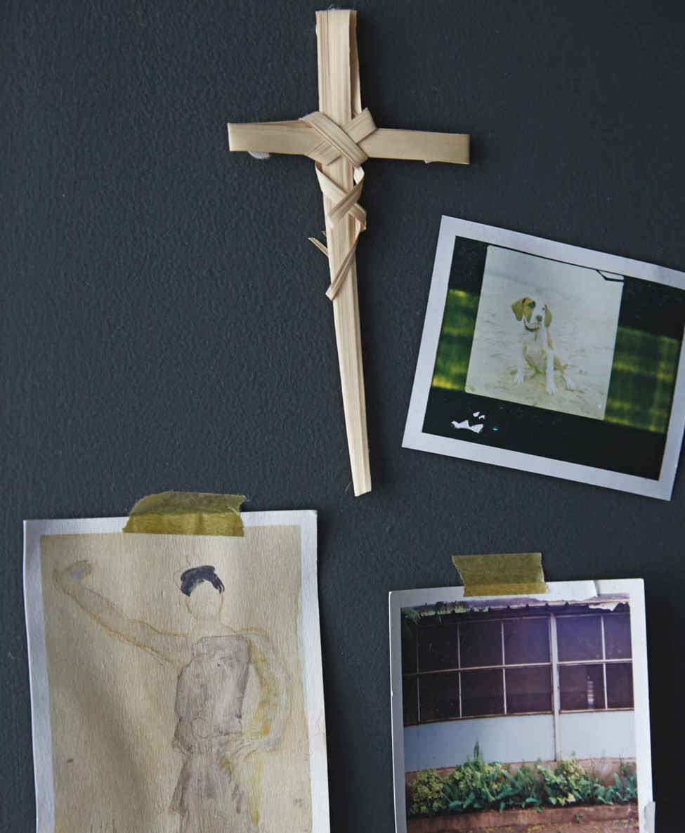 SIMPLE SNAPS. In opposition to all her nicely framed art, a postcard, two Polaroids, and a handmade grass cross are taped to the wall in a hurried but personal gesture.